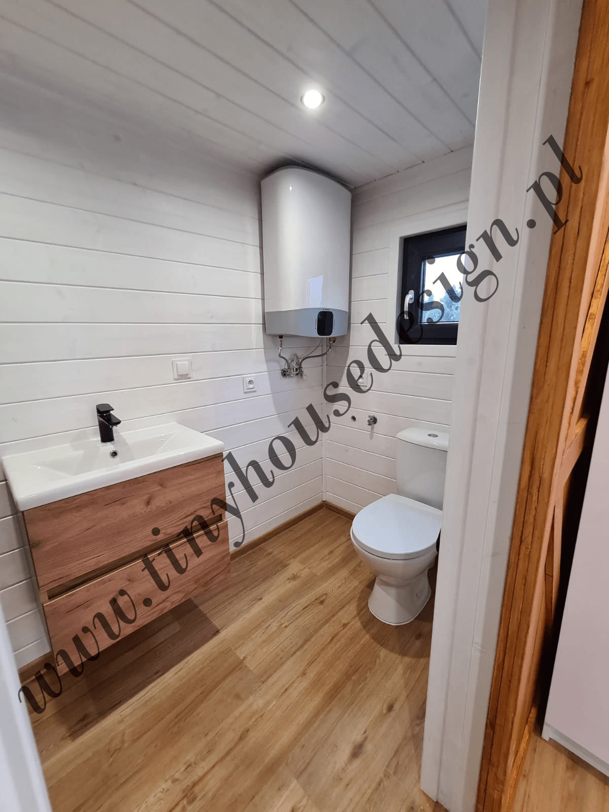 Łazienka w domku Tiny House - umywalka, boiler grzewczy i toaleta, nad toaletą okno