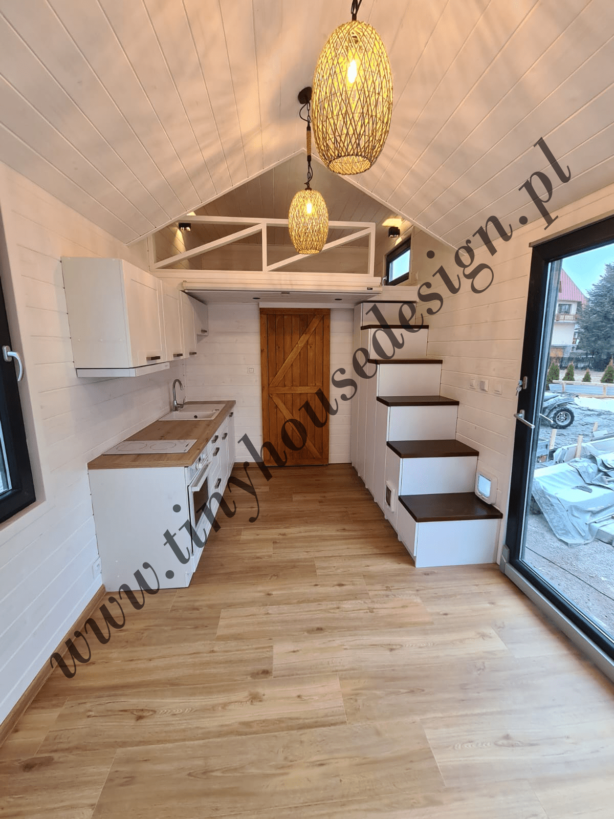 Wnętrze domku Tiny House Design - aneks kuchenny, antresola, schodki, na pierwszym planie lampy wiszące