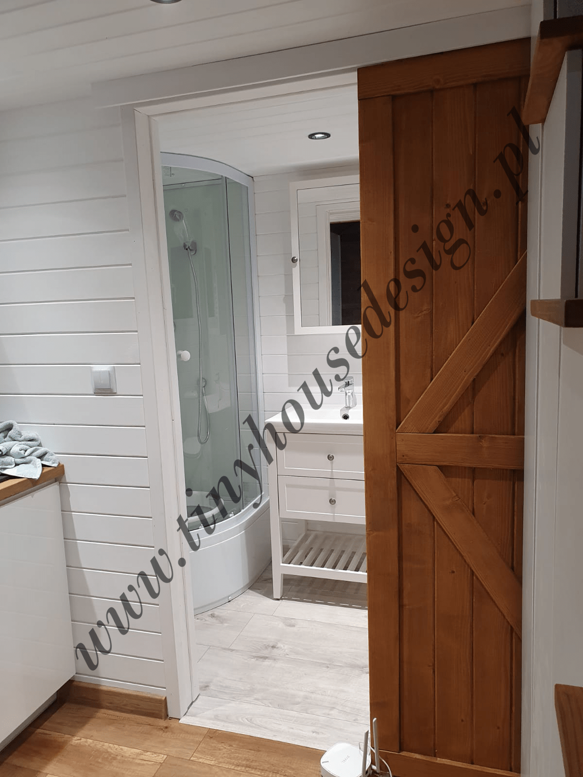 Widok do łazienki z kuchni, drewniane przesuwne drzwi